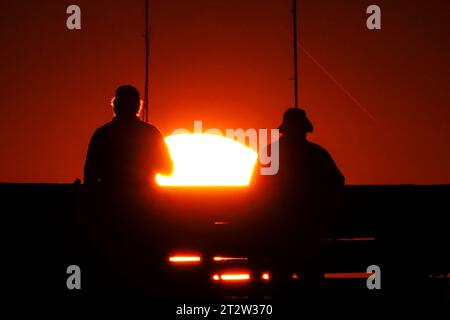 Isle Of Palms, Usa. Oktober 2023. Am Isle of Palms Pier am 19. Oktober 2023 in Isle of Palms, South Carolina, wartet eine Gruppe von Fischern, die bei Sonnenaufgang in Silhouetten auf den großen Fisch. Quelle: Richard Ellis/Richard Ellis/Alamy Live News Stockfoto