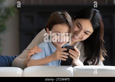 Nahaufnahme lächelnde asiatische Mutter mit Sohn, die zusammen das Telefon benutzt Stockfoto