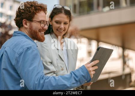 Geschäftsmann zeigt Kollegen während des Arbeitstages außerhalb des Büros etwas auf einem digitalen Tablet Stockfoto