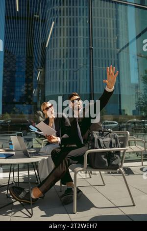 Geschäftskollegen, die mit Dokumenten arbeiten, die auf der Terrasse des Cafés sitzen und etwas zeigen Stockfoto