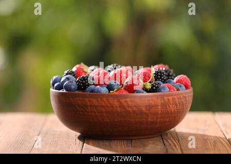 Schüssel mit verschiedenen frischen, Reifen Beeren auf Holztisch im Freien Stockfoto