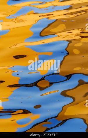 Lebendige Rot-, Orange-, Blau- und Goldtöne spiegeln sich im Wasser beim Sonnenuntergang in der Spree in Berlin wider, können als farbenfroher abstrakter Hintergrund verwendet werden. Stockfoto