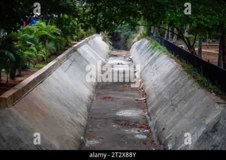 Ein Wassergraben, der in der Trockenzeit trocknet, mit Bäumen, die um den Wasserfluss wachsen. Stockfoto