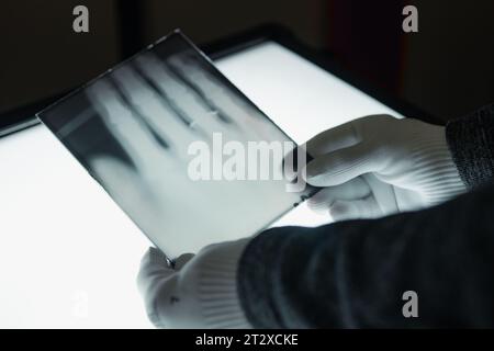 Remscheid, Deutschland. Oktober 2023. Ein Mitarbeiter des Deutschen Röntgen-Museums hält ein Röntgenbild seiner Hand, fotografiert von Wilhelm Röntgen, über einem Leuchtkasten. Historische Röntgenbilder aus dem Museum wurden für das UNESCO-Weltdokumentarerbe nominiert. (Zu dpa: "Röntgen's Pictures - Ein Museum auf dem Weg zum Weltdokumenterbe") Credit: Marius Becker/dpa/Alamy Live News Stockfoto