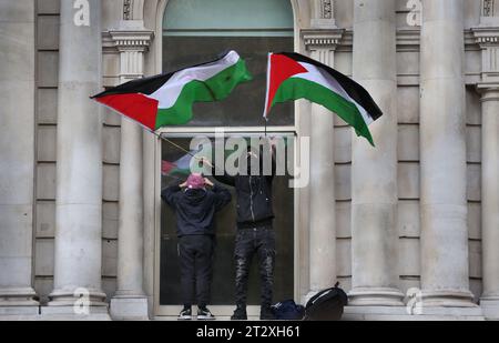 Demonstranten klettern auf Regierungsgebäude in Whitehall und schwenken palästinensische Flaggen. Anhänger Palästinas kommen zusammen, um nach dem israelischen Bombenanschlag und der drohenden Bodeninvasion israelischer Truppen in Gaza in die Downing Street zu marschieren. Dies ist die zweite Woche in Folge, in der über 100.000 Menschen auf die Straßen Londons gingen, um zu protestieren. Viele der beteiligten Organisationen rufen allgemein dazu auf, einen Waffenstillstand, die Öffnung des Übergangs Rafah nach Ägypten und humanitäre Hilfe in den Gazastreifen zu ermöglichen. (Foto: Martin Pope/SOPA Images/SIPA USA) Stockfoto