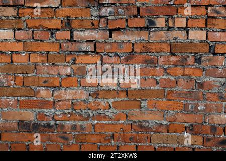 Die Textur einer alten, rauen Ziegelwand aus roten Ziegeln. Stockfoto