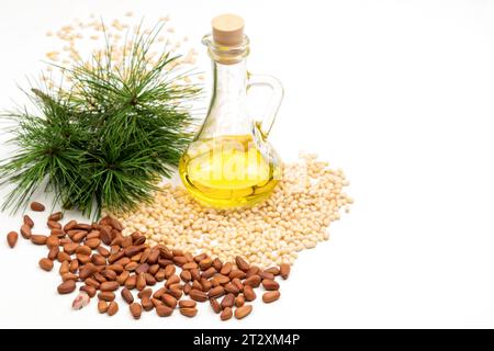 Zedernüsse ohne Schale. Pinienkerne, Flasche Öl und grüner Kiefernzweig. Draufsicht. Weißer Hintergrund. Stockfoto