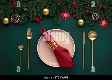 Leerer Teller, goldenes Besteck. Festliche Tischdekoration, weihnachtsdekoration. Weihnachtsfeier: Flaches Arrangement. Rote, goldene Akzente. Glänzende Kugeln, fi Stockfoto
