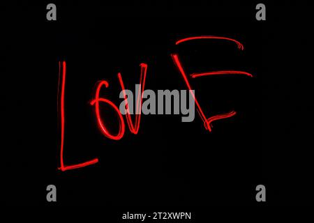 Hellrote Beschriftung mit der Freeze Light-Methode auf dem Foto zum Valentinstag, für Geschenke an Lieben. Stockfoto