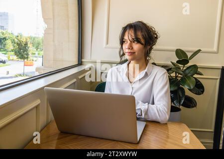Mädchen-Persona kommuniziert in sozialen Netzwerken hinter einem Laptop. Stockfoto