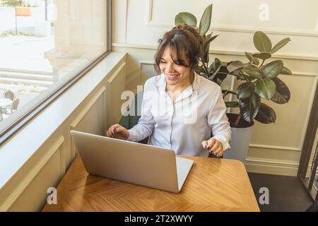 Mädchen-Persona kommuniziert in sozialen Netzwerken hinter einem Laptop. Stockfoto