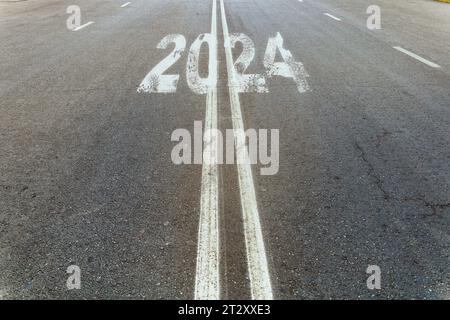 Neujahr 2024 oder einfaches Konzept. Der Text 2024 steht auf der Straße in der Mitte der Asphaltstraße. Planungs- und Aufgabenkonzept, neu l Stockfoto