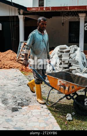Selangor, Malaysia - 21. Oktober 2023 Arbeiter mit Schubkarre bei Renovierungsarbeiten an einem Haus. Stockfoto