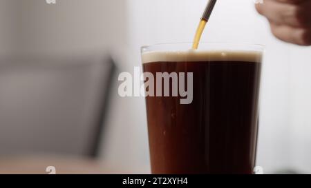 Nitro-Kaffee in dünnem Glas auf Walnusstisch machen, großes Foto Stockfoto