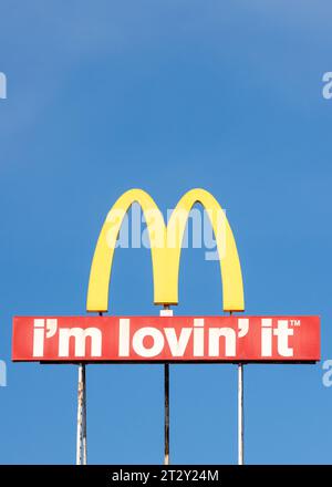 McDonalds Logo-Bogen-Schild und „I'm Lovin' IT“-Schriftzug gegen blauen Himmel Stockfoto