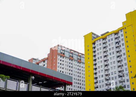 Es präsentiert ein hohes Apartmentgebäude mit einer komplexen Anordnung von Gelb- und Brauntönen, perfekt ergänzt durch einen gut ausgestatteten Parkplatz Stockfoto