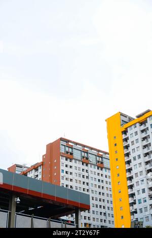 Es präsentiert ein hohes Apartmentgebäude mit einer komplexen Anordnung von Gelb- und Brauntönen, perfekt ergänzt durch einen gut ausgestatteten Parkplatz Stockfoto