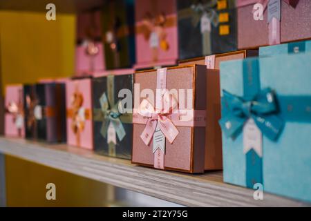 Geschenkbox-Vielfalt: Leuchtende Farben und Muster, die ordentlich auf gestuften Regalen angeordnet sind Stockfoto