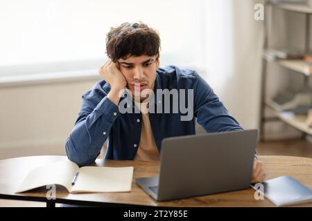 Unglücklicher überarbeiteter arabischer Geschäftsmann, der traurig am Arbeitsplatz sitzt Stockfoto