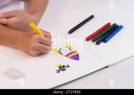 Mädchen zeichnet mit Buntstiften auf einem weißen Blatt Papier. Buntstifte und Kinder zeichnen auf weißem Hintergrund. Nahaufnahme einer Hand eines Kindes mit einem Stift und dra Stockfoto