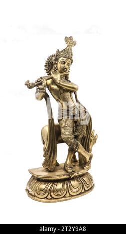 goldene Statue des Herrn krishna mit Details, ein Avatar von vishnu, der Flötenmusik in der Nähe einer Kuh in einer Tanzposition spielt, isoliert Stockfoto