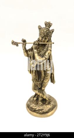 goldene Messingstatue des hindugottes krishna in ländlicher Kleidung, die Flöte auf weißem Hintergrund spielt Stockfoto