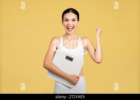 Fröhliche europäische Frau, die Waage hält und Gewichtsverlust feiert Stockfoto