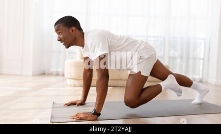 Aktiver afroamerikanischer junger Mann, der zu Hause Cardio-Übungen macht Stockfoto