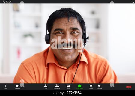 Lächelnder indischer Mann mittleren Alters in Kopfhörern lächelnd in die Kamera Stockfoto