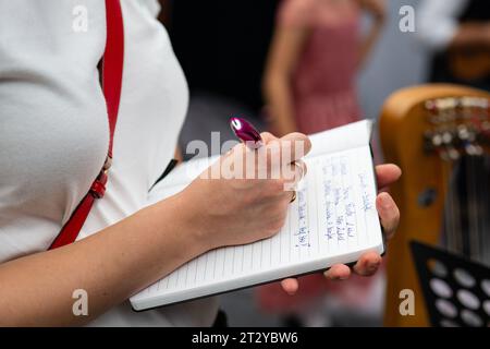 Frau macht Notizen mit einem Stift in einem Notizbuch Stockfoto