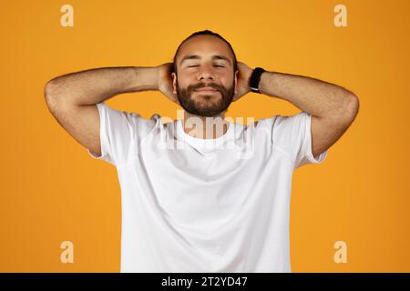 Positiv ruhiger junger kaukasier mit Bart in weißem T-Shirt ruhen, entspannen Sie mit geschlossenen Augen Stockfoto