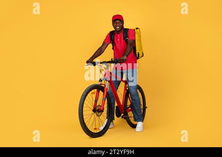 Ich bin froh, dass ein attraktiver Kurier in Uniform mit einem Rucksack auf dem Fahrrad unterwegs ist Stockfoto
