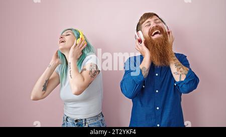 Ein Mann und eine Frau, die Musik hören, die über einen isolierten pinken Hintergrund tanzt Stockfoto