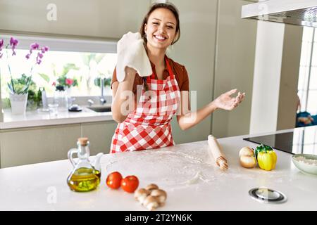 Junge schöne hispanische Frau lächelt zuversichtlich Teig Pizza mit den Händen in der Küche halten Stockfoto