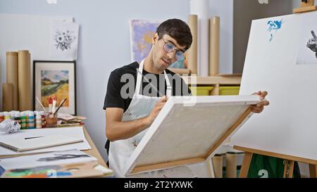 Die fesselnde Geschichte eines jungen, gutaussehenden hispanischen Mannes, der intensiv in eine Kunststunde vertieft ist und elegant ein Porträt in einem pulsierenden Kunststudio malt, b Stockfoto