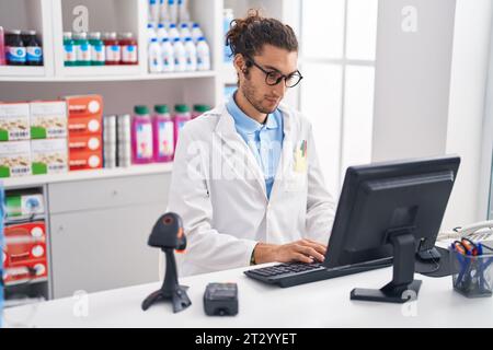 Junger hispanischer Apotheker mit Computer in der Apotheke Stockfoto