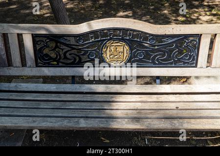 Jerewan, Armenien - 14. September 2023: Vorderansicht der städtischen Holzbank mit Wappen Jerewans auf der Straße in Jerewan am sonnigen Herbsttag. Ja Stockfoto