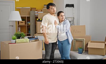 Mann und Frau, die sich in ihrem neuen Zuhause mit entspanntem Ausdruck umarmen Stockfoto