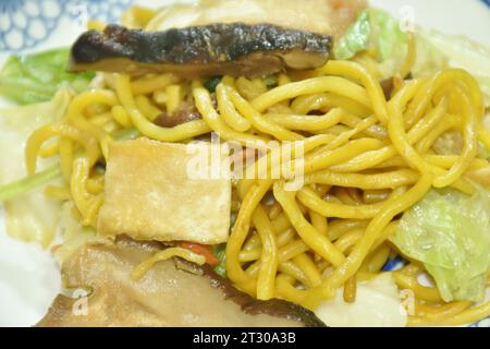 Gebratene gelbe Nudeln mit Kohl und Tofu vegetarisches Essen umrühren Auf dem Teller Stockfoto