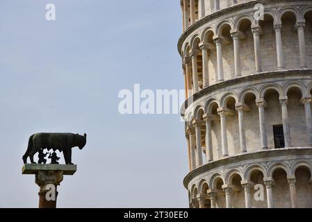 Pisa, Italien. September 2023. Statue von Romulus und Remus, die den Wolf Capitolina vor einem Abschnitt des Schiefen Turms säugen. Stockfoto