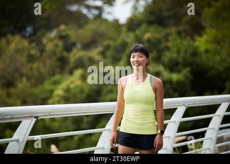 Außenporträt einer glücklichen jungen asiatischen Sportlerin Stockfoto