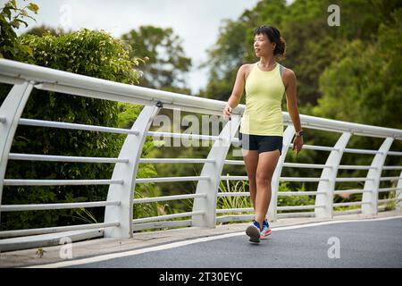 Junge asiatische Frau Joggerin, die sich im Stadtpark erholt Stockfoto