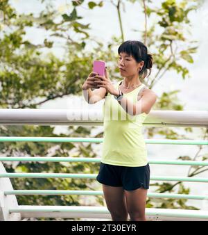 Junge asiatische Frau, die draußen ein Selfie macht, mit dem Handy Stockfoto