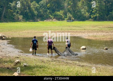 Tauchen Sie ein in die uralte Tradition, während drei Männer geschickt Netzfischen am ruhigen Ufer des Patenggang Lake betreiben. Diese Szene erfasst Stockfoto