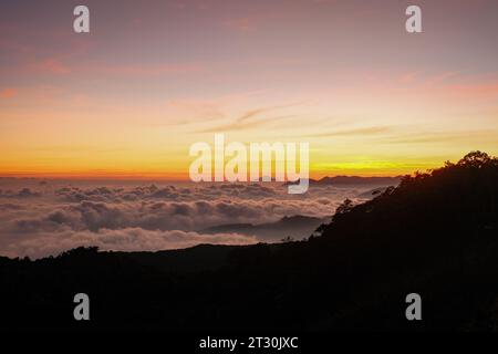 Erleben Sie die ätherische Schönheit des Sonnenaufgangs über Kawah Putih, während goldene Töne die Wolken zieren. Die Leinwand der Natur erwacht in einer atemberaubenden Ausstellung Stockfoto