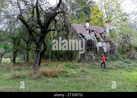 Wanderer mit Blick auf die Ruinen eines alten Hauses, Überreste des alten verlassenen deutschen Dorfes Kunc tief im Wald von Kocevski rog, Dolenjska, Slowenien Stockfoto