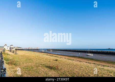 Blick entlang des Strandes mit Hafen bei Ebbe und Pier im Kent Resort Stadt Herne Bay an einem frühen Morgen im Sommer. Klarer blauer Himmel, heller Sonnenschein. Stockfoto