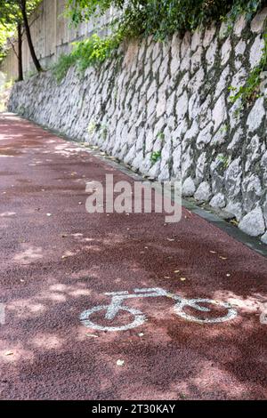 Die Fahrradspur neben der Steinmauer mit viel Grün Stockfoto