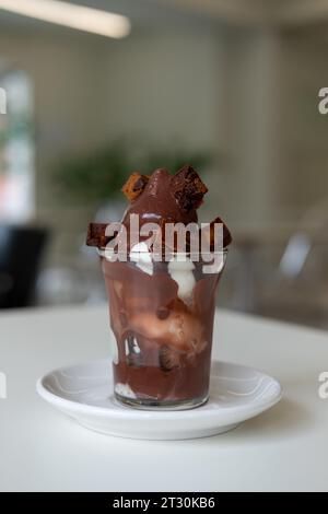 Eis mit Schokoladensirup und Brownie in einem Plastikbecher auf dem Tisch Stockfoto