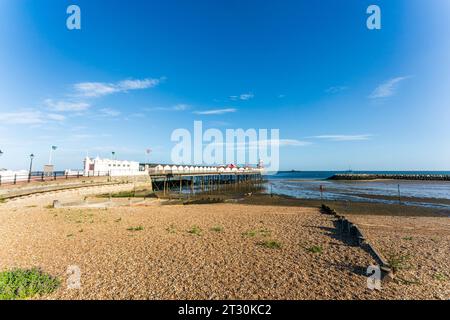 Der Strand mit Hafen bei Ebbe und der Pier im Kent Resort Stadt Herne Bay an einem Sommermorgen früh. Klarer blauer Himmel, heller Sonnenschein. Stockfoto